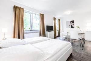 a white bedroom with a large bed and a desk at Apartments Köln in Cologne