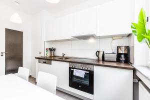 a kitchen with white cabinets and a stove top oven at Apartments Köln in Cologne