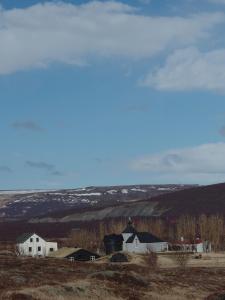 a group of houses in a field with snow on the hills at Guesthouse Gamli Bær in Húsafell