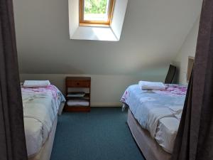 two beds in a room with a window at Magenta Cottage in Tumbarumba