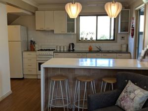 a kitchen with a large island with bar stools at Magenta Cottage in Tumbarumba