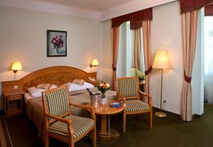 a hotel room with a bed and a table and chairs at Parkhotel Golf Marianske Lazne in Mariánské Lázně