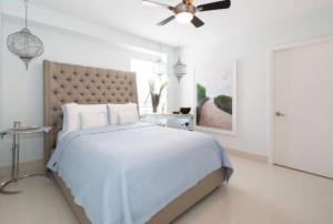 een witte slaapkamer met een bed en een plafondventilator bij Heart of South Beach / Modern Apartment / Ocean Drive - Carlyle in Miami Beach