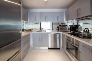 a kitchen with white cabinets and stainless steel appliances at Heart of South Beach / Modern Apartment / Ocean Drive - Carlyle in Miami Beach