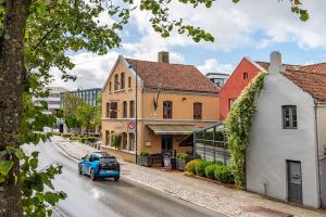 a blue car driving down a street with buildings at GamlaVærket Gjæstgiveri og Tracteringssted in Sandnes