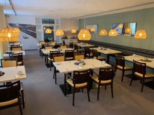 a dining room with tables and chairs and chandeliers at Hotel Garni Max Zwo in Dingolfing