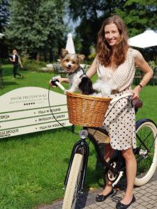 Eine Frau, die mit einem Hund in einem Korb Fahrrad fährt. in der Unterkunft Dwór Prezydencki Boutique Hotel & SPA in Tarnów