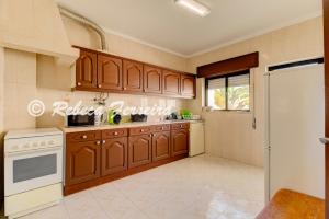eine Küche mit Holzschränken und einem weißen Gerät in der Unterkunft Villas2go2 T1 Miramar in Carvoeiro