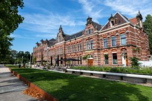 een groot bakstenen gebouw met een gazon ervoor bij Conscious Hotel Westerpark in Amsterdam