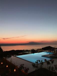 a large swimming pool with a sunset in the background at Villa Salina Luxury Pool Villa in Kechria