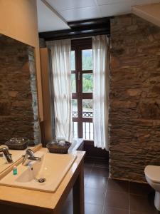 baño con lavabo y aseo y ventana en Hotel Mirador de Barcia, en Ribeira de Piquin