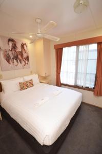1 dormitorio con 1 cama blanca grande y ventilador de techo en Tasman Holiday Parks - Merool on the Murray, en Echuca