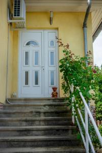 a white door on a yellow house with stairs at Virágos vendégház in Keszthely
