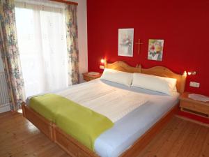 1 dormitorio con 1 cama grande y pared roja en Oberstockinghof, en Saalfelden am Steinernen Meer