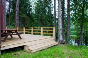 a wooden deck with a picnic table in the woods at Kempings Ozolkalns in Cēsis