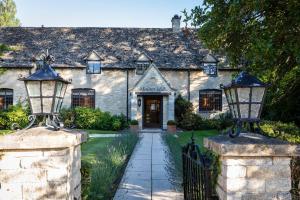 an old stone house with a gate and two lights at Minster Mill Hotel in Minster Lovell