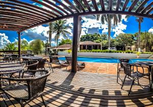 a patio with tables and chairs next to a swimming pool at Vila Jacaré in Brotas