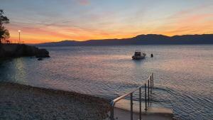 a boat in a body of water at sunset at Apartments 4M in Kostrena