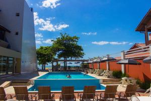 uma piscina num hotel com cadeiras e uma pessoa a nadar em Spazio Marine Hotel - Guaratuba em Guaratuba