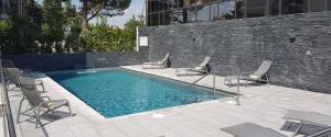 une piscine avec des chaises et un mur en briques dans l'établissement Golden Tulip Aix en Provence, à Aix-en-Provence