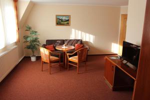 ein Wohnzimmer mit einem Tisch, Stühlen und einem Sofa in der Unterkunft Pension Zur Grünen Eiche in Kaulsdorf