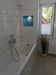 a white bath tub with a shower in a bathroom at Gästehaus Twee Linden in Warnemünde