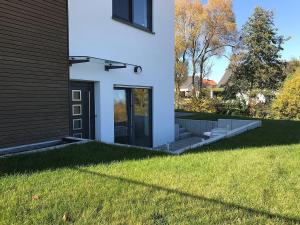ein weißes Haus mit einer Tür und einem Rasenhof in der Unterkunft Ferienwohnung Deifel in Schömberg