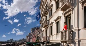 a woman standing on a balcony of a building at Londra Palace Venezia in Venice