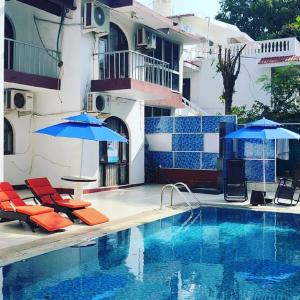 einen Pool mit Stühlen und Sonnenschirmen neben einem Gebäude in der Unterkunft Athi Resorts in Bogmalo Beach
