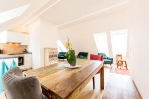 eine Küche und ein Wohnzimmer mit einem Holztisch und Stühlen in der Unterkunft Große Dachgeschosswohnung im Herzen von Graz in Graz