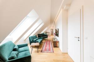 ein Wohnzimmer mit zwei grünen Sofas und einem Teppich in der Unterkunft Große Dachgeschosswohnung im Herzen von Graz in Graz