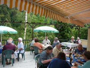 a group of people sitting at tables under an umbrella at Hotel Waldhaus-Hutzelhöh in Ruhla