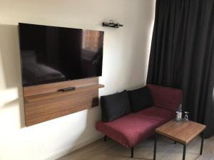 een woonkamer met een rode bank en een flatscreen-tv bij Hotel am Schlosstheater in Fulda