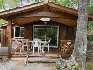 a cabin with a table and chairs on a deck at Pyla Chalet et mobilhom 6 personnes Magda in La Teste-de-Buch