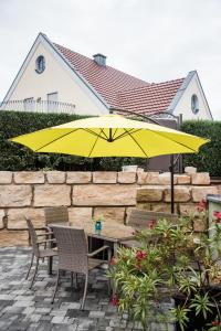 une table et des chaises avec un parapluie jaune dans l'établissement Ferienwohnung/Businessapartment, à Wolframs-Eschenbach
