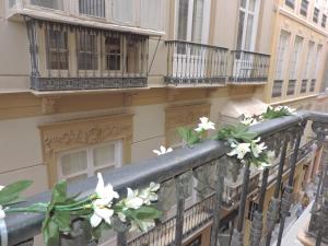 un balcón con flores blancas en la barandilla en Casita de Santos, en Málaga