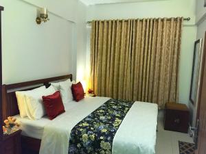 ein Schlafzimmer mit einem großen Bett mit roten Kissen in der Unterkunft "Service Apartments Karachi" Beach View in Karatschi