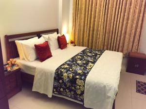 a bedroom with a large bed with red pillows at Beach View Service Apartments Karachi in Karachi