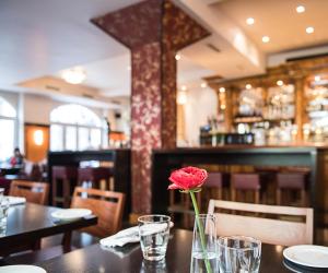 una rosa en un jarrón sobre una mesa en un restaurante en Hotel Ritzi en Múnich