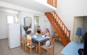 un groupe de personnes assises à une table dans une cuisine dans l'établissement Résidence Odalys Le Village des Amareyeurs, au Château-dʼOléron