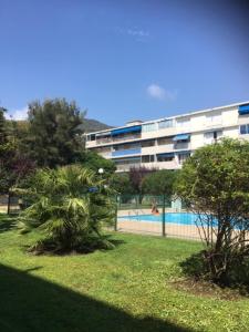 a building with a palm tree next to a swimming pool at LesJardinsFleuris in Mandelieu-La Napoule