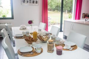 uma mesa de jantar branca com comida em MAISON MAUPAS Chambre Rouge em Bellesserre
