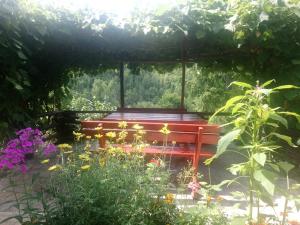 un banco rojo sentado en un jardín con flores en Little heaven 2, en Mandići