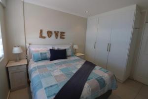 a bedroom with a bed with a love sign on the wall at Cozumel 410 in Umdloti