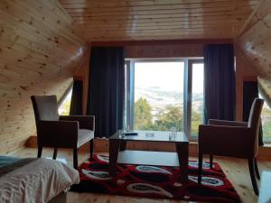 a bedroom with a table and chairs and a large window at Buta Hotel Lerik in Lerik