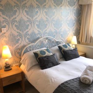 a bedroom with a white bed with blue wallpaper at The Strawbury Duck Inn in Darwen