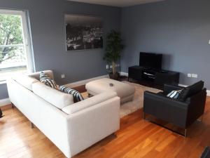 uma sala de estar com um sofá branco e uma televisão em Luxurious Penthouse Apartment 1 , City Centre em Kilkenny