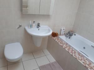 a white bathroom with a sink and a toilet and a tub at Luxurious Penthouse Apartment 1 , City Centre in Kilkenny +7 photos