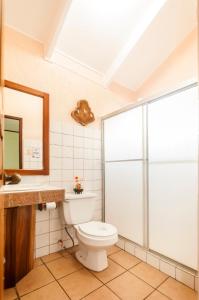 a bathroom with a toilet and a sink and a mirror at Cadillac Rock Beach Hotel in Jacó