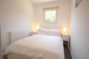 1 dormitorio con 1 cama blanca y 2 almohadas en Lake Lodges en Chichester